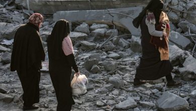 Personas en Gaza buscan objetos entre escombros de un edificio bombardeado por Israel.