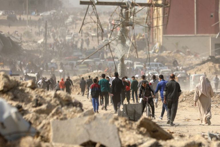 Población en Gaza corren hacia puesto de reparto de ayuda humanitaria.